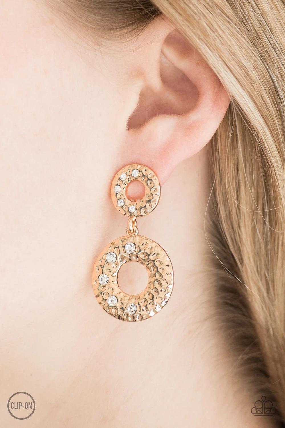 Paparazzi Accessories Sophisticated Shimmer - Gold Hammered in glistening textures, a circular gold frame gives way to a slightly larger gold frame, creating an elegant lure. Dainty white rhinestones are sprinkled across the frames, adding a glittery fini