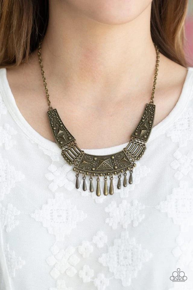 Paparazzi Accessories STEER it Up - Brass Embossed and studded in tribal inspired details, glistening brass plates connect below the collar in a fierce fashion. Dainty teardrop brass beads drip from the center of the pendant, creating a delicate fringe. F