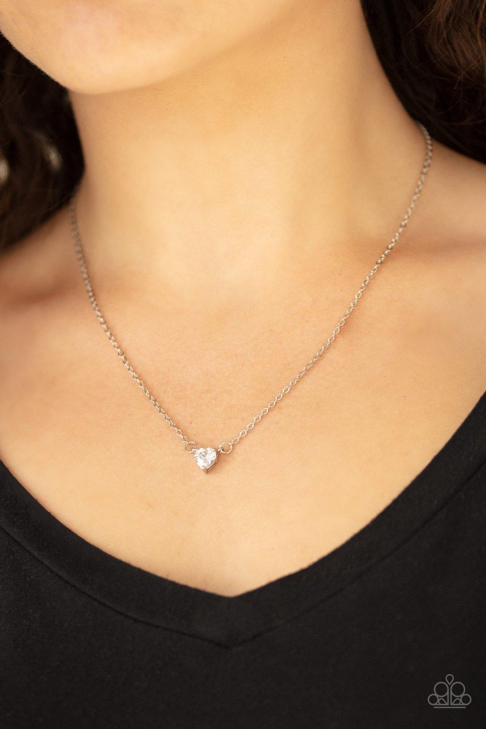 Paparazzi Accessories Heartbeat Bling - White A dainty heart-shaped white cubic zirconia swings below the collar for a timelessly romantic look. Features an adjustable clasp closure. Sold as one individual necklace. Includes one pair of matching earrings.