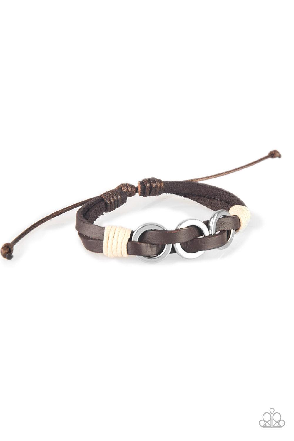 Paparazzi Accessories Off-Road Tourist - Brown Infused with white twine cording, antiqued silver rings are threaded along strands of brown leather bands for a rustic look. Features an adjustable sliding knot closure. Jewelry
