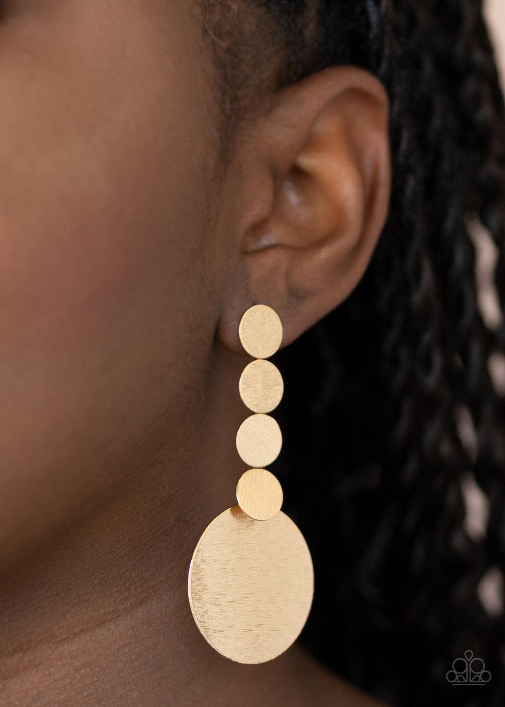 Paparazzi Accessories Idolized Illumination - Gold Featuring a delicately scratched surface, a row of dainty gold discs connects to a large gold disc, creating a bold display. Earring attaches to a standard post fitting. Sold as one pair of post earrings.