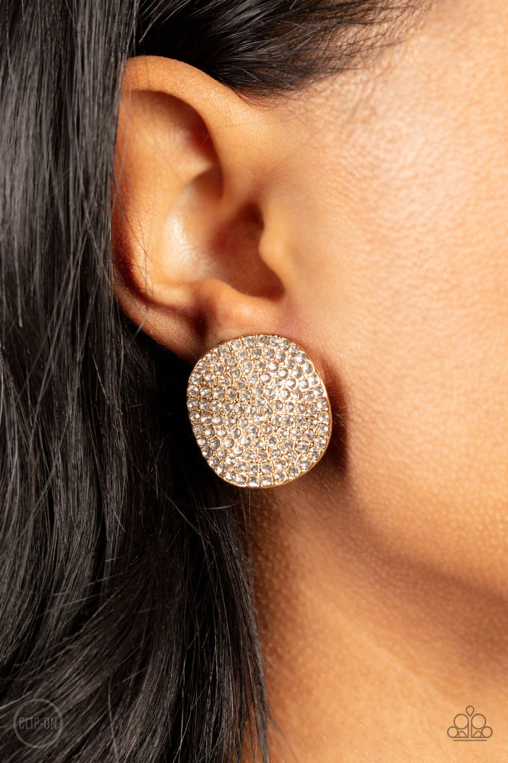 Paparazzi Accessories Lunch at the Louvre *Clip-on The front of a warped gold disc is encrusted in row after row of blinding white rhinestones, resulting in a refined display. Earring attaches to a standard clip-on fitting. Sold as one pair of clip-on ear