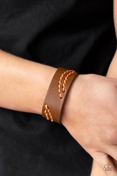 Paparazzi Accessories Harmonic Horizons - Orange Marigold cording is stitched across the front of a brown leather band, creating curved patterns. Features an adjustable snap closure. Sold as one individual bracelet. Bracelets