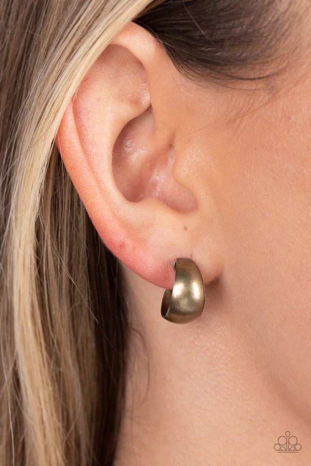 Paparazzi Accessories Burnished Beauty - Brass A thick bar of brass curls around the ear into a fashionable hoop. The dramatic curvature of the hoop is heightened by its high sheen finish, making a lasting impression. Earring attaches to a standard post f