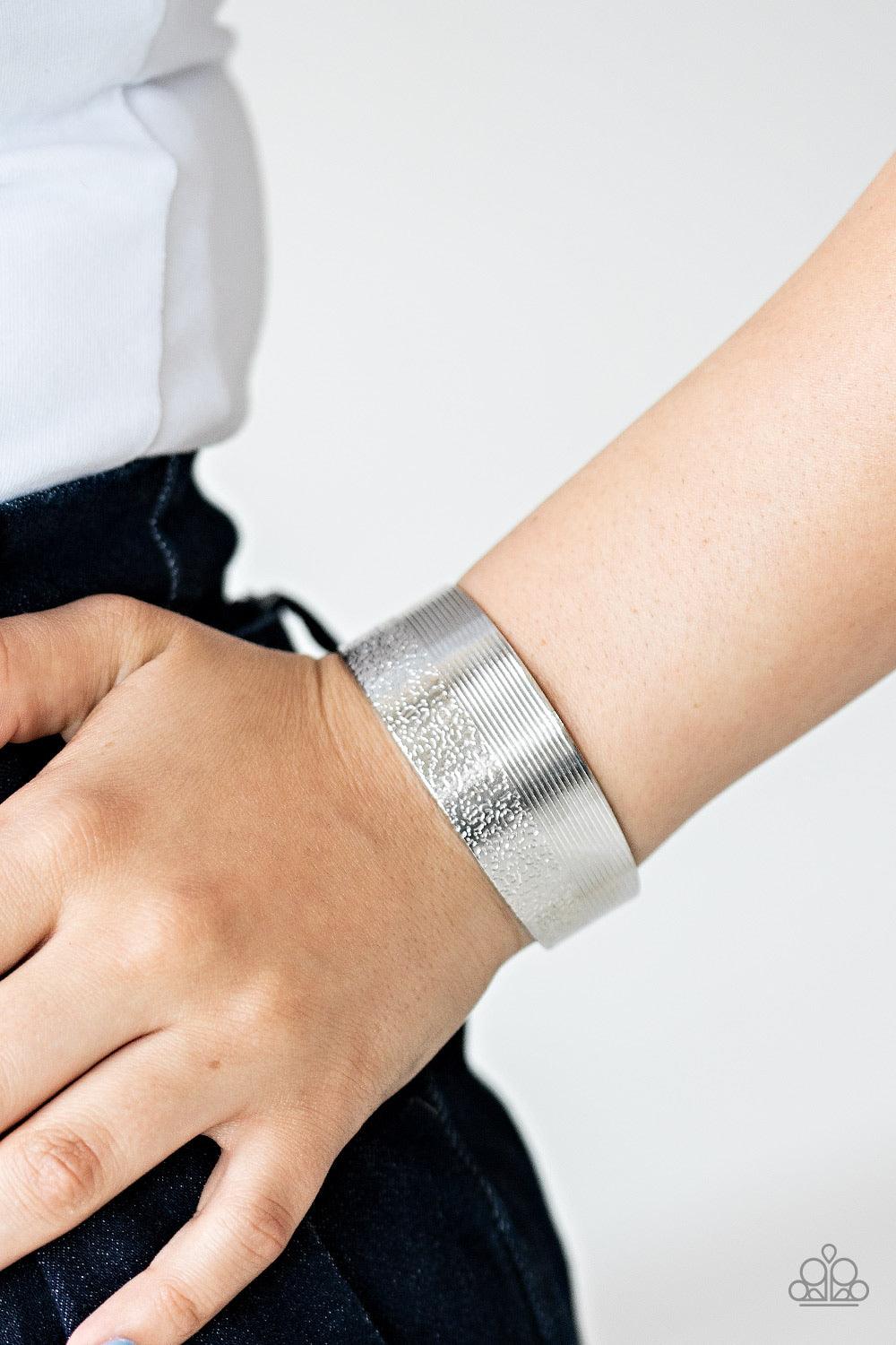 Paparazzi Accessories Mixed Vibes - Silver One half of a thick silver cuff is engraved in stacked linear lines while the other half is hammered in a row of tactile textures, creating a collision of texture around the wrist. Sold as one individual bracelet