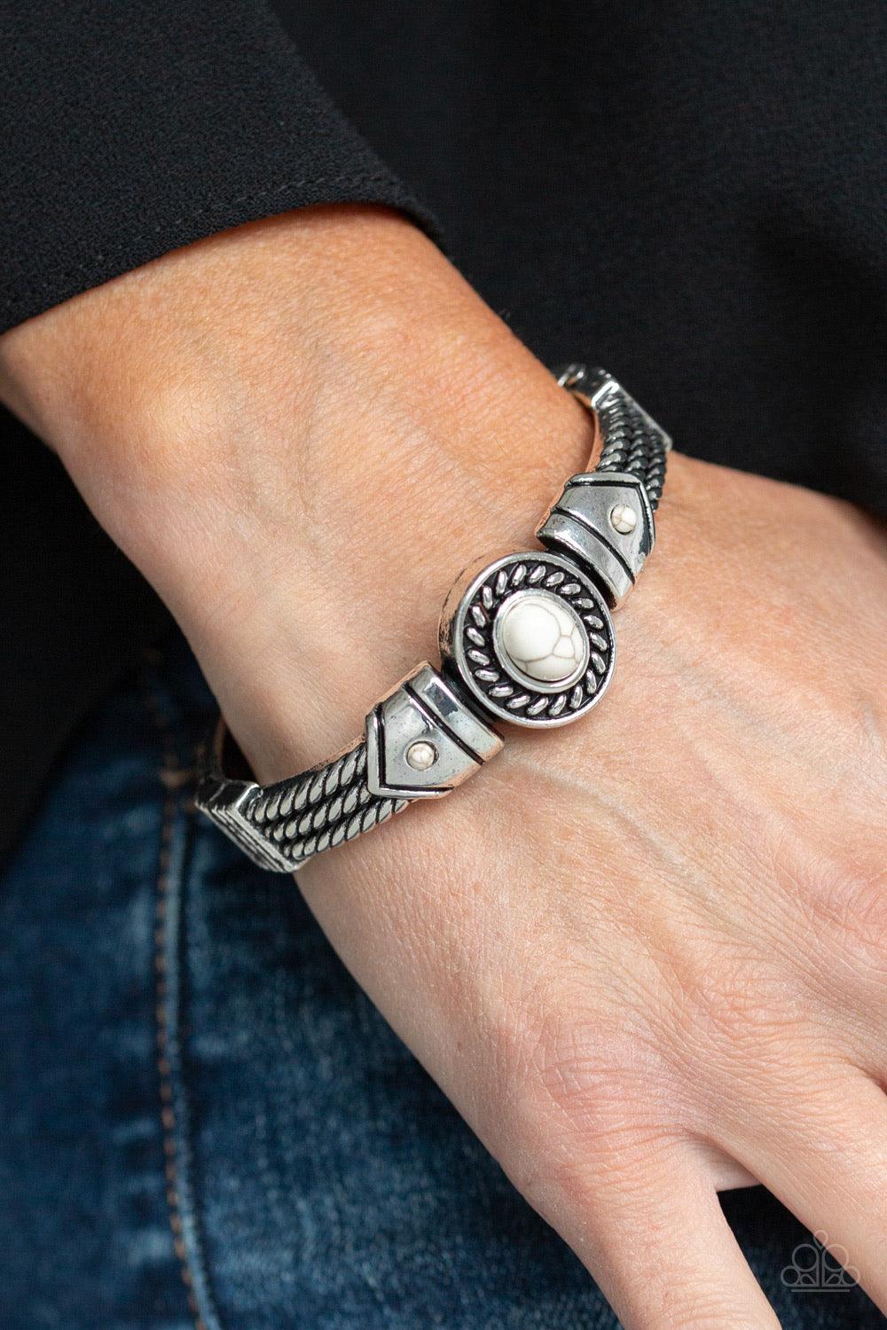 Paparazzi Accessories Tribal Soul ~White Featuring metallic rope-like patterns, an ornate bangle-like cuff curls around the wrist. Refreshing white stones dot the center of the ornate frame for a seasonal flair. Features a hinged closure. Jewelry