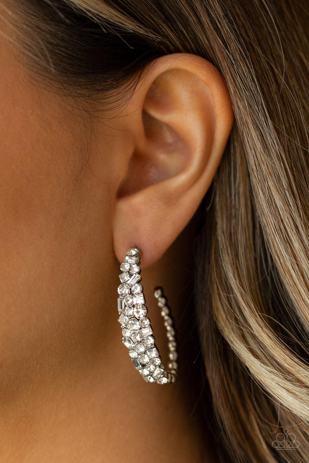 Paparazzi Accessories The Glitzy Conscience - Black The front of a hook-shaped gunmetal hoop is encrusted in a collision of glassy white rhinestones for a blinding look. Earring attaches to a standard post fitting. Hoop measures approximately 1" in diamet