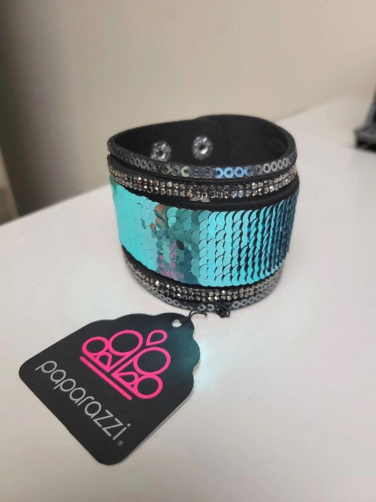 Paparazzi Accessories Heads Or MERMAID Trails - Blue Three aurum emerald-cut rhinestones are encrusted along three brass bands radiating with smooth surfaces and sections of glittery aurum rhinestones for an edgy fashion. Features a stretchy band for a fl
