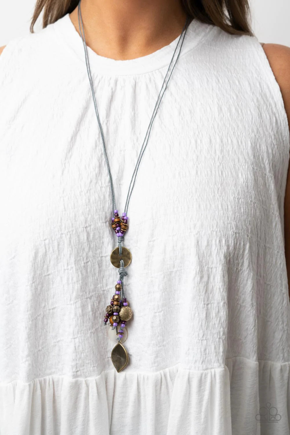 Paparazzi Accessories Knotted Keepsake - Purple An earthy assortment of purple and plum seed beads, rustic brass discs, and wooden accents glide along lengthy strands of gray cording that knot around a hammered brass disc. Tassels of matching beads, a whi
