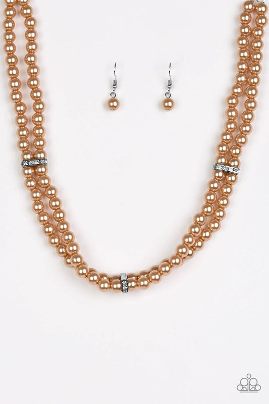 Paparazzi Accessories Put on Your Party Dress - Brown Pinched between white rhinestone encrusted frames, strands of classic brown pearls layer below the collar for a timeless look. Features an adjustable clasp closure. Sold as one individual necklace. Inc