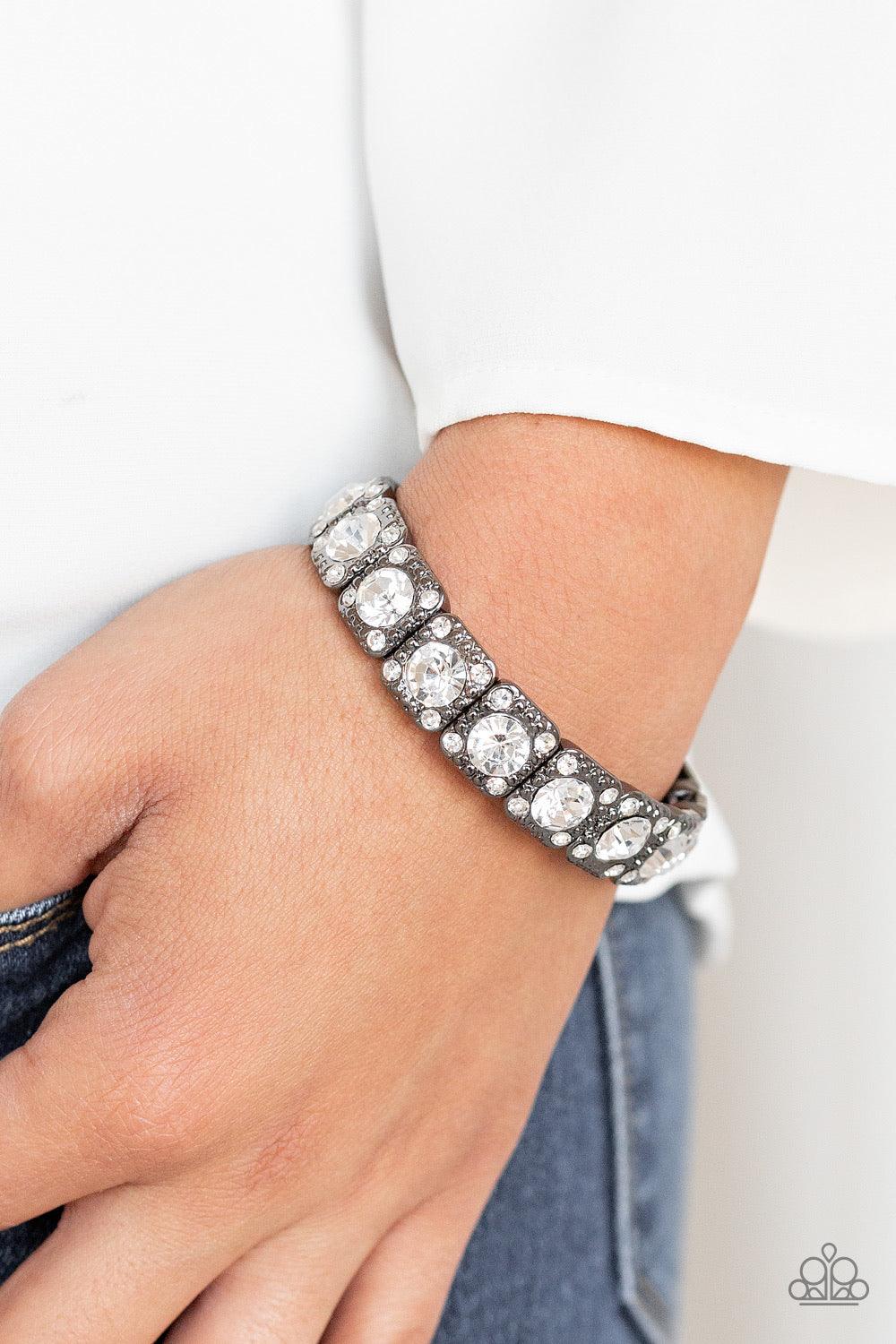 Paparazzi Accessories Blinged Out - Black Featuring oversized white rhinestone centers, studded gunmetal frames radiating in glassy white rhinestones are threaded along a stretchy band around the wrist for a glamorous fashion. Jewelry