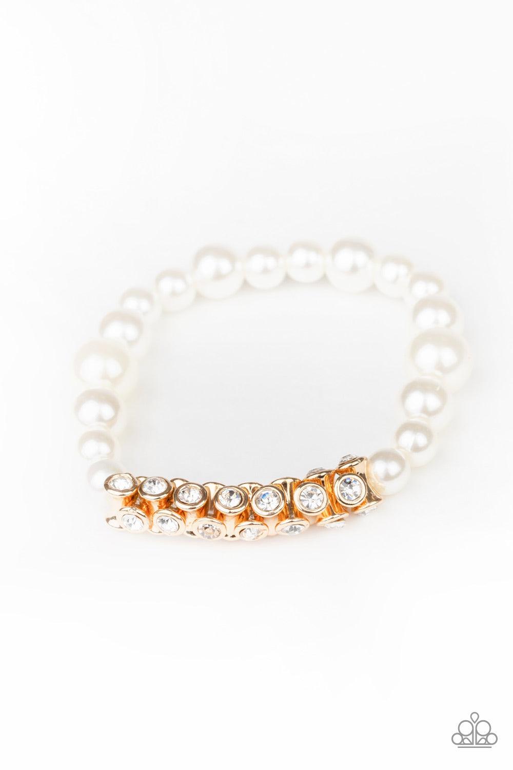 Paparazzi Accessories Traffic-Stopping Sparkle - Gold A collection of white pearls and white rhinestone dotted gold frames are threaded along stretchy bands around the wrist, creating a sparkling centerpiece. Jewelry