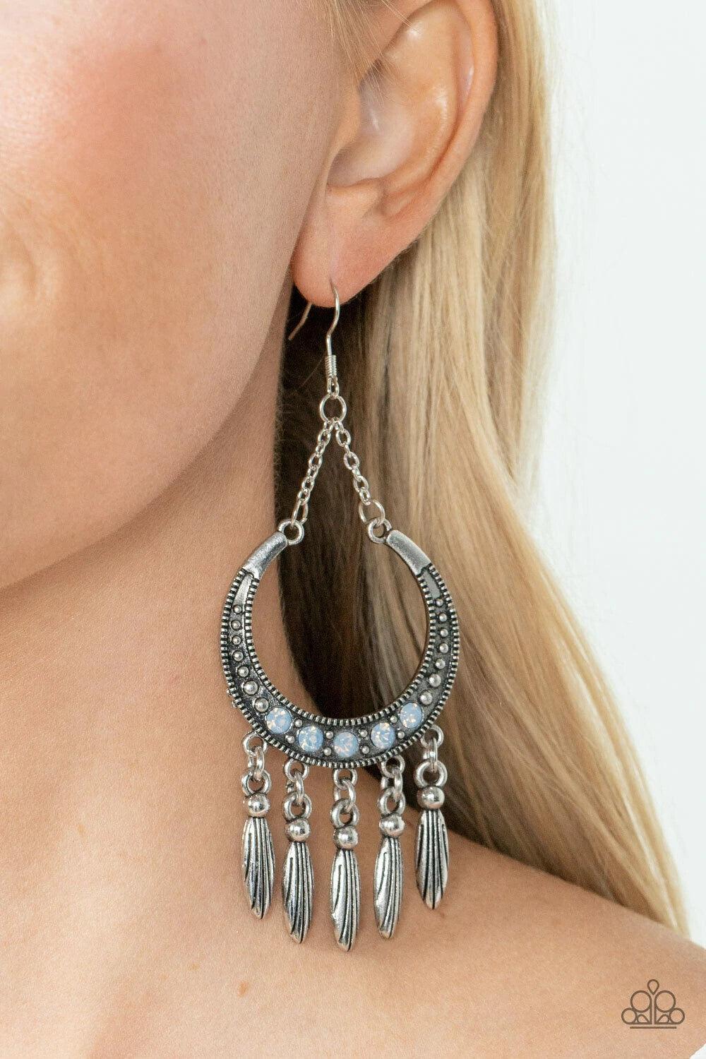 Paparazzi Accessories Day to DAYDREAM - Blue A row of blue opal rhinestones adorns the center of a studded silver half moon frame. Tassels of classic and textured silver beads cascade from the bottom of the frame, creating a dreamy fringe. Earring attache