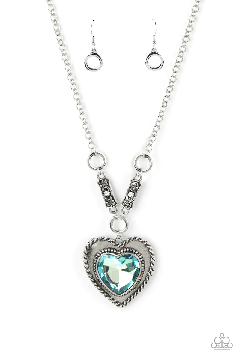 Paparazzi Accessories Heart Full of Fabulous - Blue Bordered in spun silver ribbons, an oversized blue heart gem is pressed into a silver heart frame below the collar. The flirtatious pendant attaches to silver rings and decorative silver frames dotted in