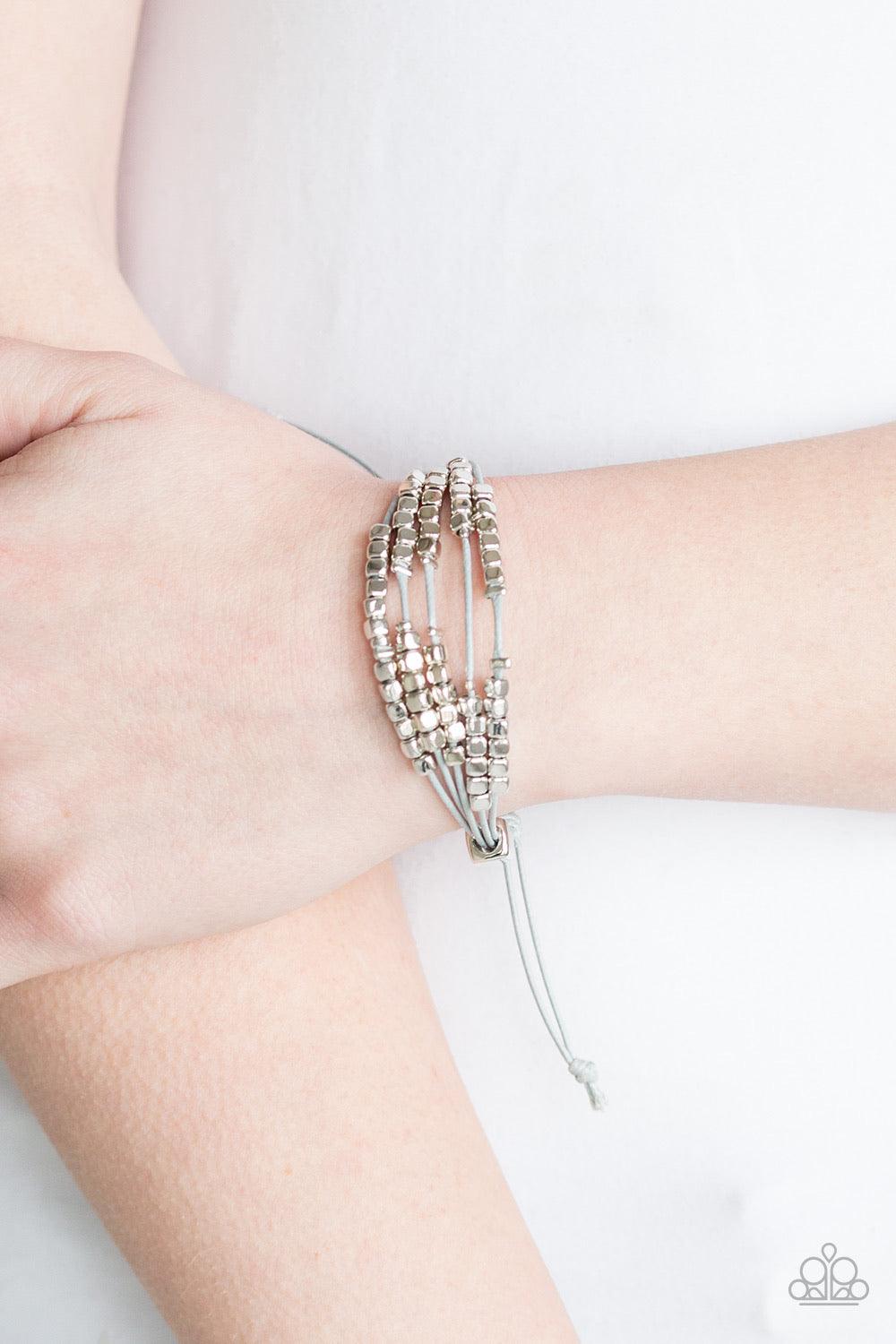Paparazzi Accessories Modern Minimalism - Silver A collection of dainty silver beads and glistening silver cubes are threaded along strands of shiny gray cording around the wrist for a minimalist inspired look. Features an adjustable sliding knot clos Jew