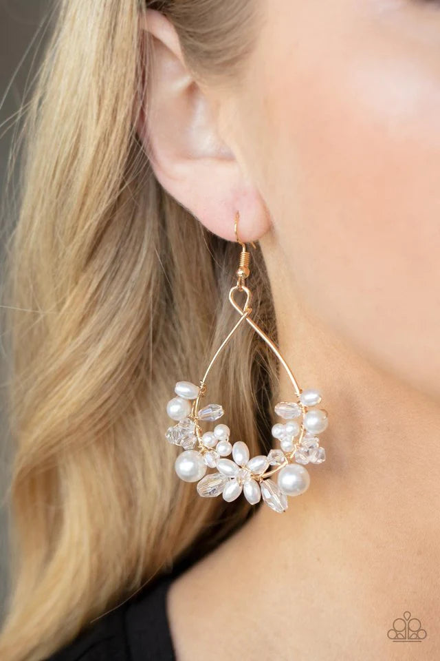 Paparazzi Accessories Marina Banquet - Gold A bubbly collection of white pearls and white crystal-like beads are threaded along the bottom of a dainty gold wire hoop, creating twinkly floral accents. Earring attaches to a standard fishhook fitting. Jewelr