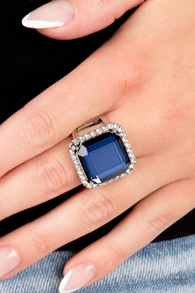 Paparazzi Accessories Slow Burn - Blue A lavish square Skydiver gem, encased in a border of dainty white rhinestones, makes a head-turning centerpiece as it gleams with an industrial edge atop the finger. Features a stretchy band for a flexible fit. Sold