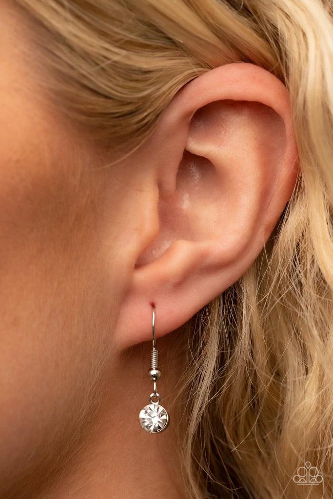 Paparazzi Accessories Finding My Forever - White Bordered in a ribbon of glassy white rhinestones, an oversized white heart-shaped gem seemingly floats at the bottom of an extended silver chain. A shimmery silver chain tassel dances from the bottom of the