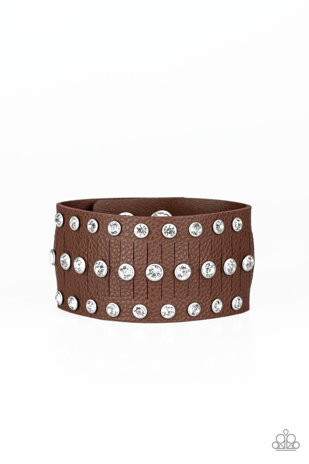 Paparazzi Accessories Now Taking The Stage - Brown Pressed into sleek silver frames, glittery white rhinestones are studded across a thick brown leather band featuring a center lined with slits for a sassy finish. Features an adjustable snap closure. Sold