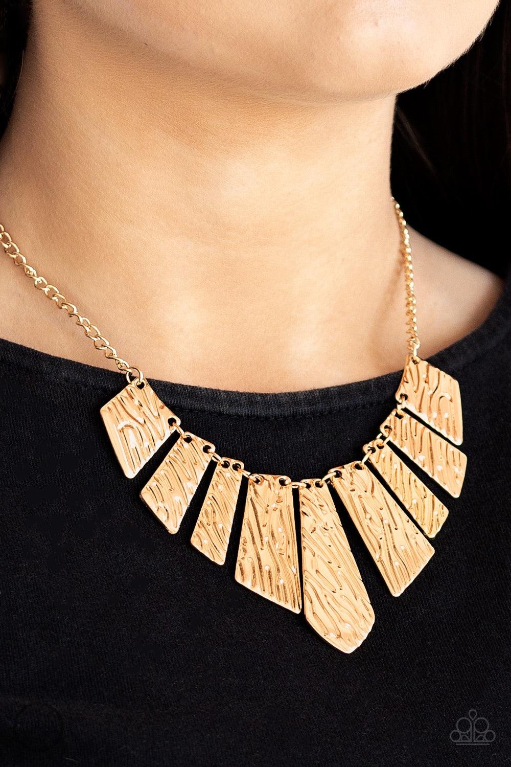 Paparazzi Accessories Texture Tigress - Gold Embossed in rippling patterns, a collection of angular gold plates swing from the bottom of a glistening gold chain, creating an edgy geometric fringe below the collar. Features an adjustable clasp closure. Jew