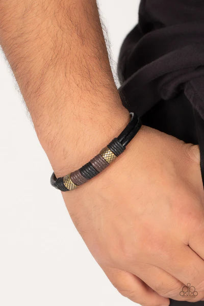 Paparazzi Accessories Forest Dweller - Brass A rustic pair of textured brass beads are knotted in place with black and brown cording around the center of a black leather band, resulting in a rugged centerpiece. Features an adjustable sliding knot closure.