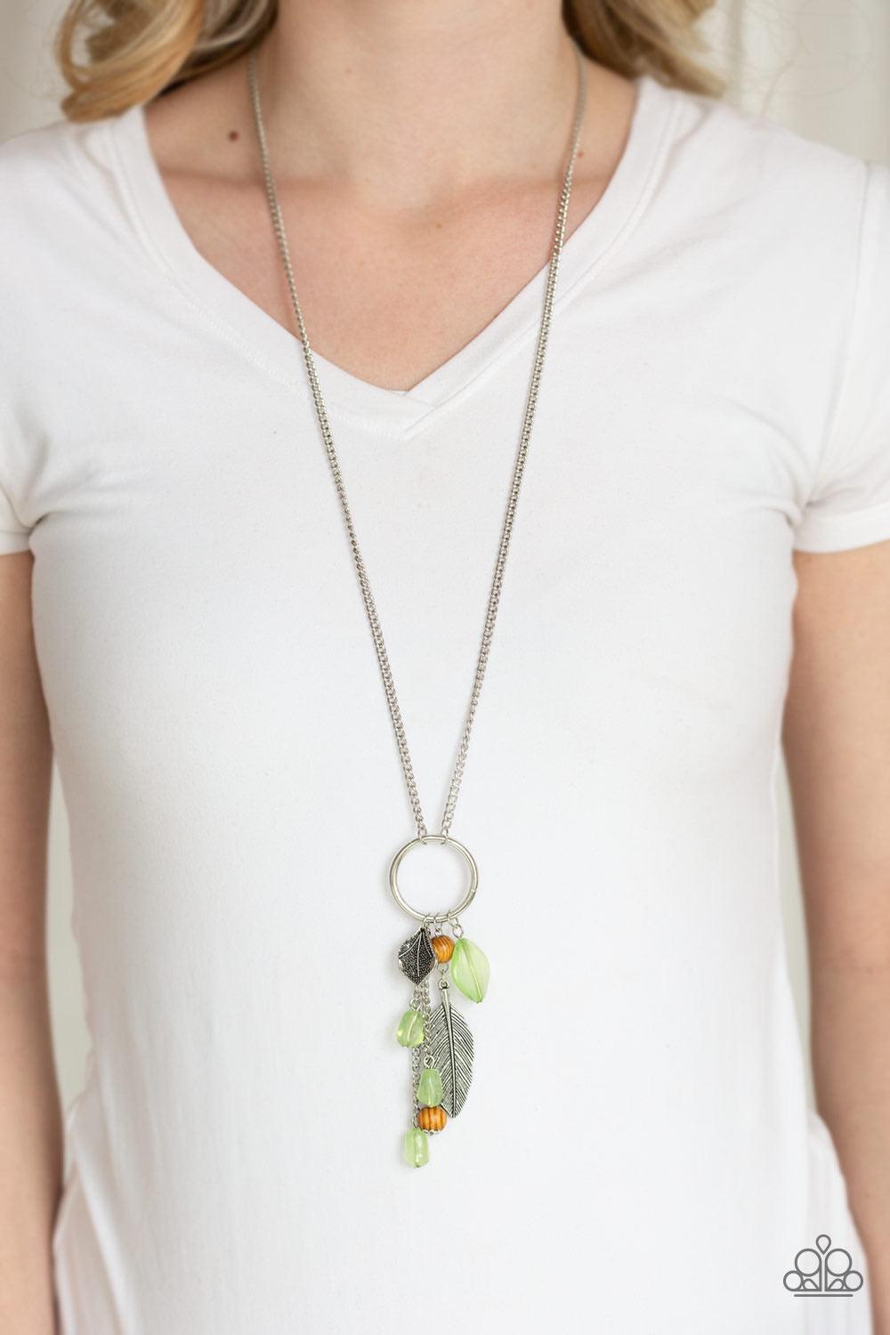 Paparazzi Accessories Sky High Style - Green Infused with shimmery silver chains, a collection of earthy brown beads, cloudy green beads, and glistening silver feather charms swing from the bottom of a bold silver hoop. The whimsical tassel attaches to a