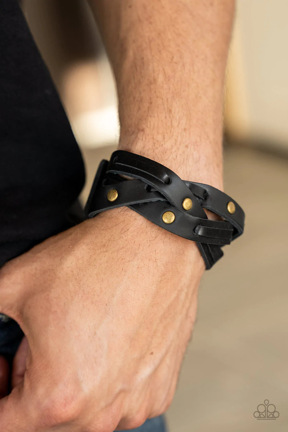 Paparazzi Accessories Rugged Roundup - Brass Featuring sections of brass studs and black leather laces, black leather bands weave into a rugged braid around the wrist. Features an adjustable snap closure. Sold as one individual bracelet.
