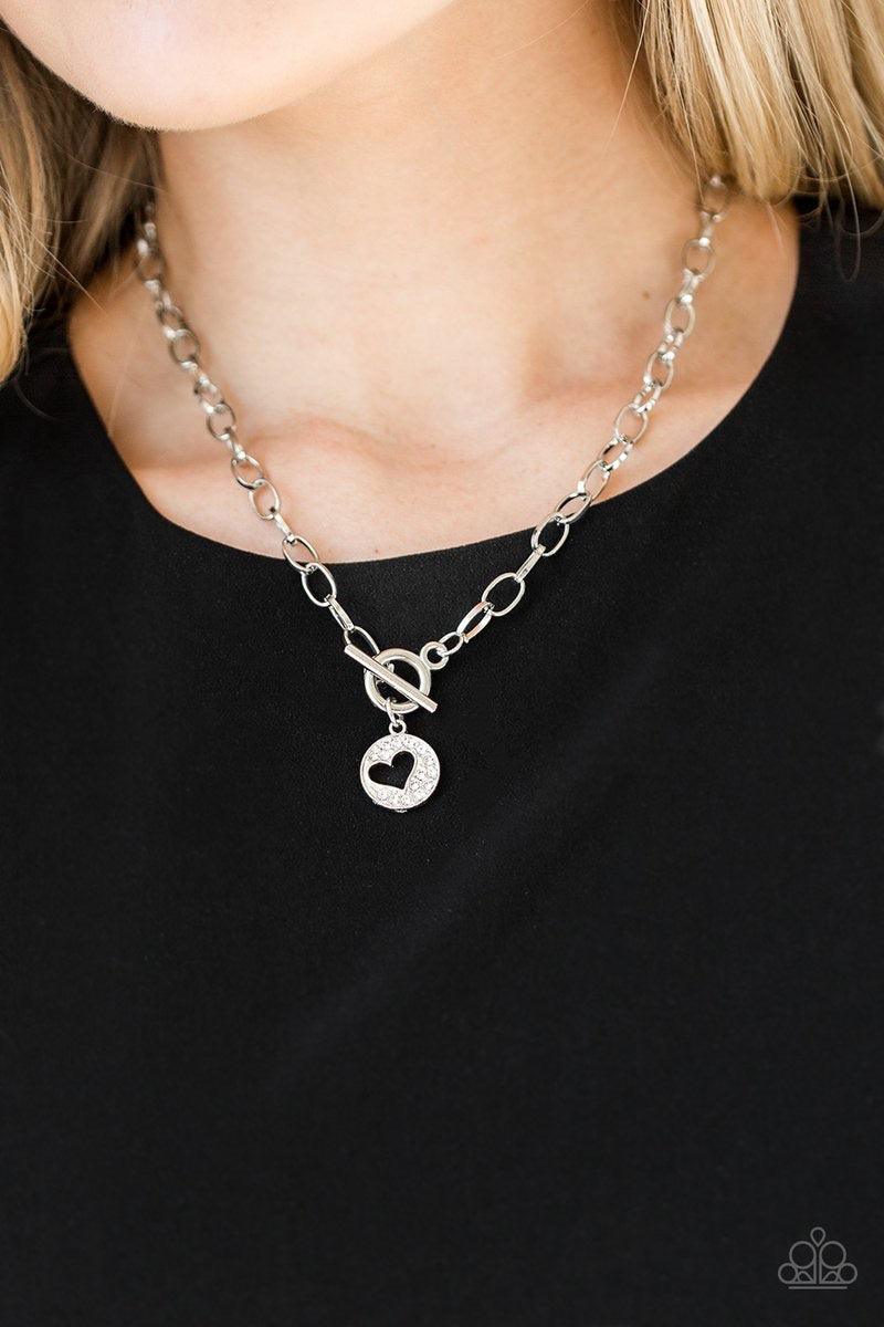 Paparazzi Accessories Heartbeat Retreat - White Radiating with glittery white rhinestones, an airy heart pendant swings from the bottom of a glistening silver chain below the collar for a flirty flair. Features a toggle clasp. Sold as one individual neckl