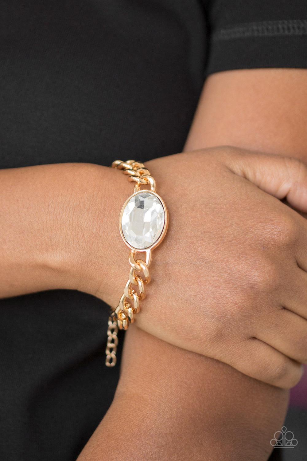 Paparazzi Accessories Luxury Lush - Gold An oversized white gem attaches to a bold gold chain, creating a dramatic centerpiece atop the wrist. Features an adjustable clasp closure. Jewelry