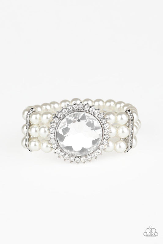 Paparazzi Accessories Speechless Sparkle - White Threaded along stretchy bands, strands of pearly white beads are held in place with white rhinestone encrusted fittings around the wrist. Bedazzled in a ring of glassy white rhinestones, a dramatically over