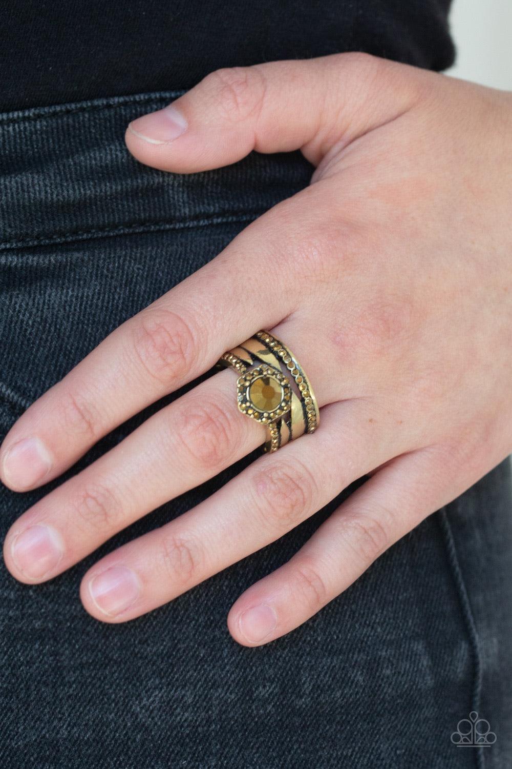 Paparazzi Accessories Modern Maven - Brass A collision of glistening brass bands and aurum rhinestone encrusted bands stack across the finger. Featuring a glittery aurum rhinestone center, a brass hexagon frame crowns the top of the layered bands for an e