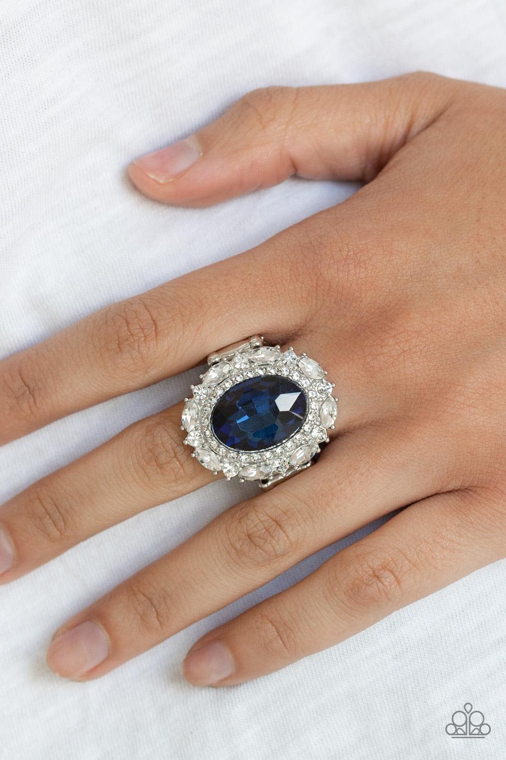 Paparazzi Accessories Show Glam - Blue An oversized oval blue gem is pressed into the center of a round silver frame encrusted in mismatched white rhinestones for a glamorous look. Features a stretchy band for a flexible fit. Jewelry