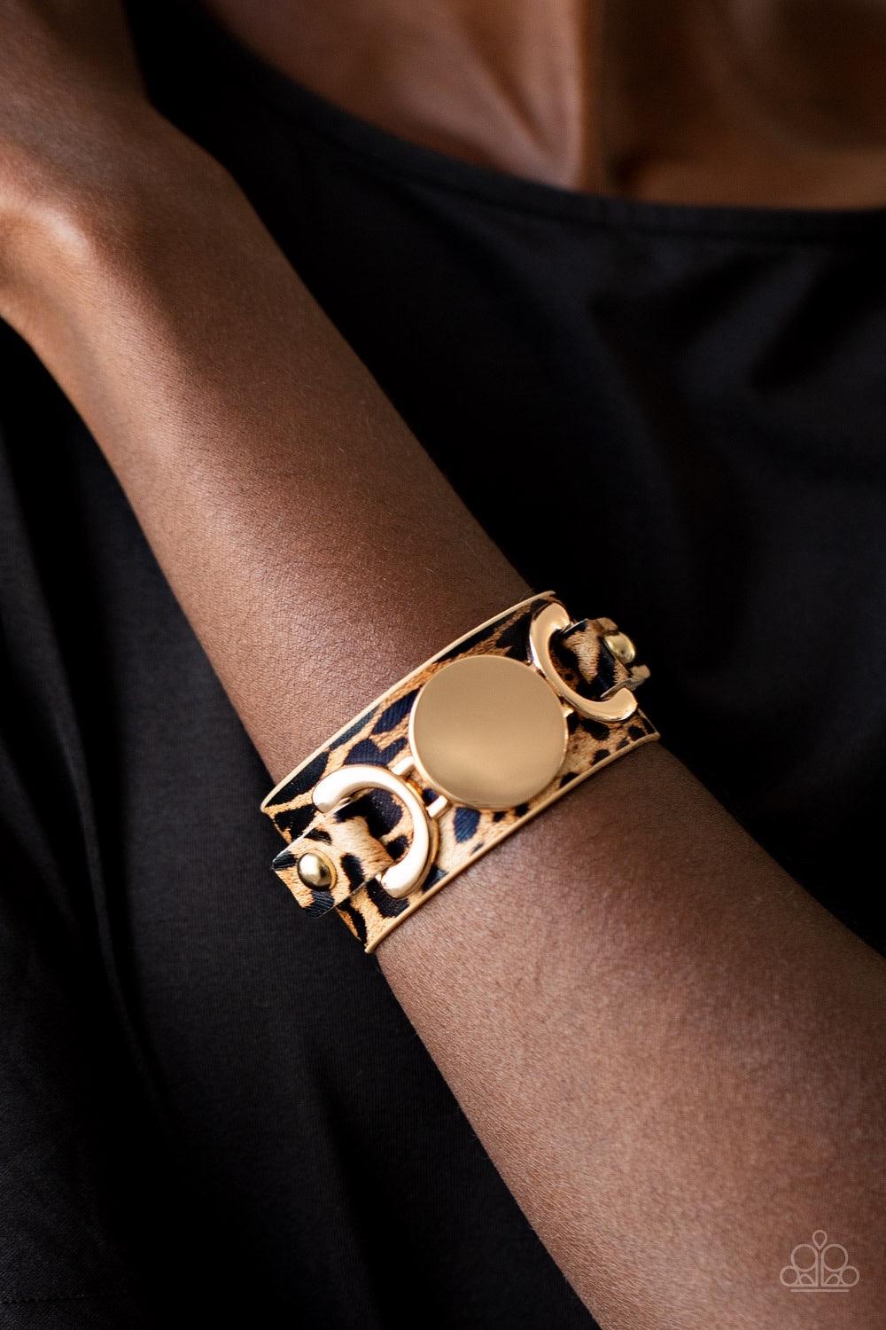 Paparazzi Accessories Your Claws Are Showing - Gold A golden buckle-like centerpiece is studded in place across the front of a thick leather band painted in brown cheetah print. Features an adjustable snap closure. Sold as one individual bracelet. Jewelry