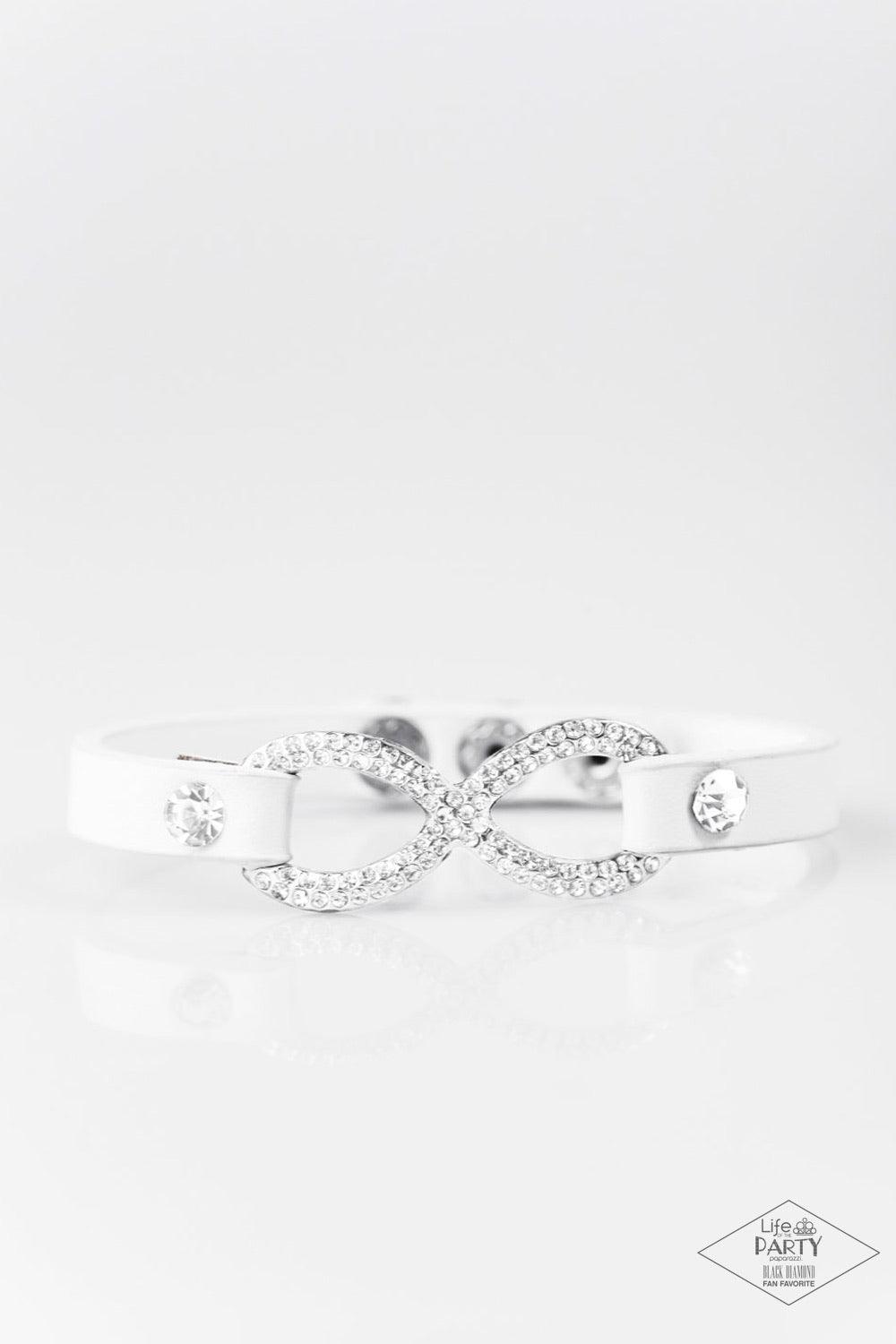 Paparazzi Accessories Innocent Till Proven GLITZY - White A skinny strip of white leather attaches to a silver infinity symbol encrusted in glittery rhinestones. Flanked by two dazzling solitaire rhinestones, the glitzy design creates an incandescent cent