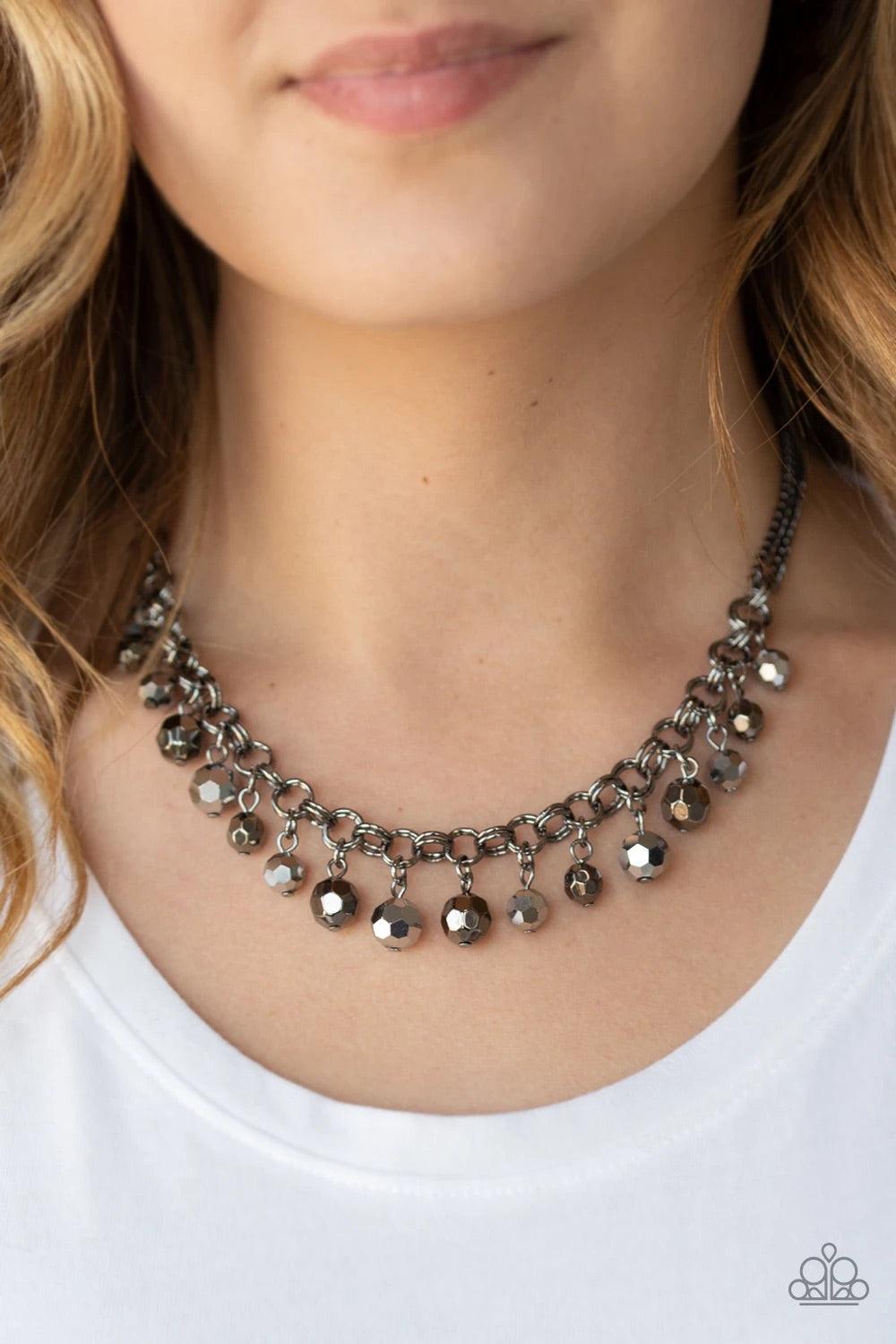Paparazzi Accessories And The Crowd Cheers - Black A collection of faceted gunmetal and hematite beads swing from the bottom of a double-link gunmetal chain, creating a blinding fringe below the collar. Features an adjustable clasp closure. Sold as one in