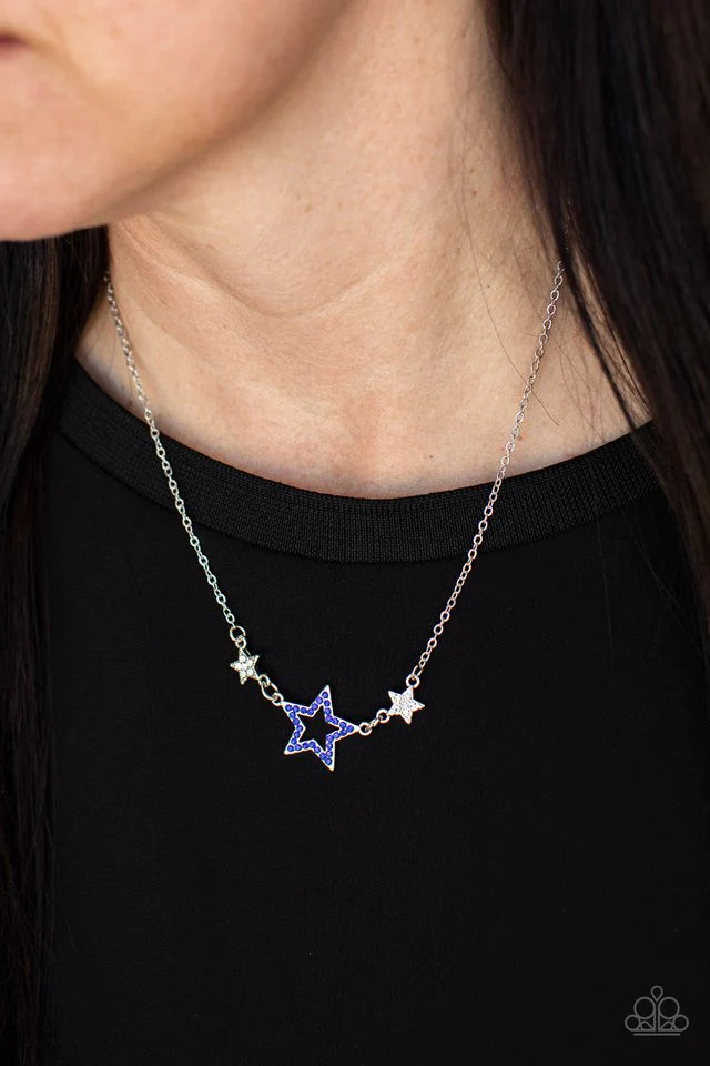 Paparazzi Accessories United We Sparkle - Blue A blue rhinestone encrusted silver star is flanked by two dainty white rhinestone encrusted silver stars, creating a sparkly patriotic pendant below the collar. Features an adjustable clasp closure. Sold as o