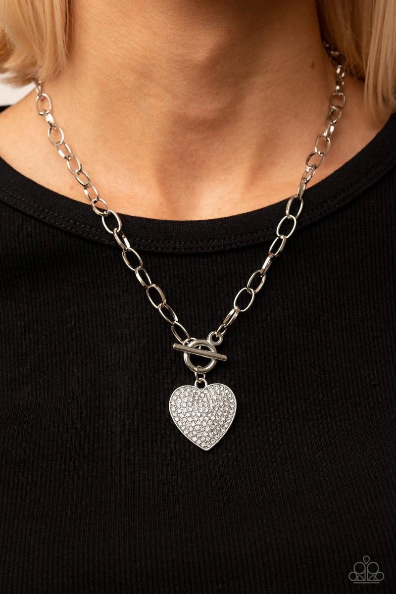 Paparazzi Accessories If You LUST - White A white rhinestone dotted silver heart frame sparkles from a toggle closure at the center of an oval silver linked chain for a flirtatious fashion. Features a toggle closure. Sold as one individual necklace. Inclu