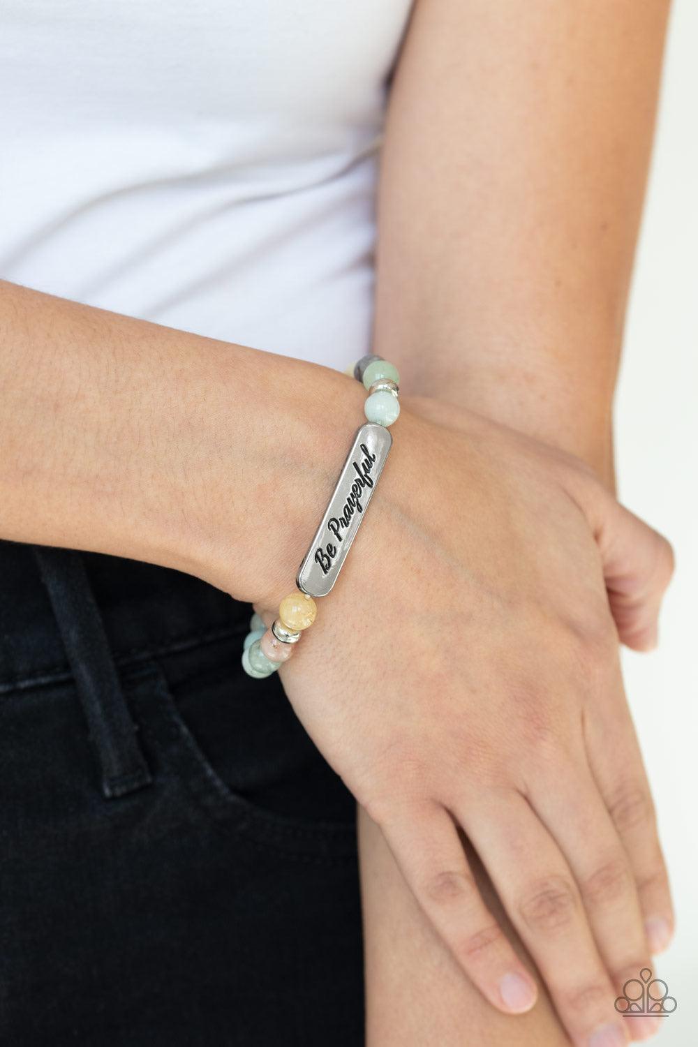Paparazzi Accessories Be Prayerful - Green Infused with dainty silver accents, a collection of glassy stone beads and a shimmery silver frame stamped in the phrase, "Be Prayerful", are threaded along a stretchy band around the wrist for an inspirational l