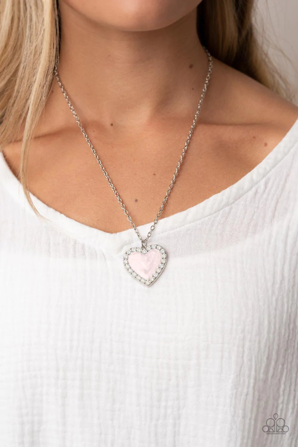 Paparazzi Accessories Heart Full of Luster - Pink Bordered in a row of opal white rhinestones, a silver frame is painted in a glossy pink finish at the bottom of a silver chain for a flirtatious finish. Features an adjustable clasp closure. Sold as one in