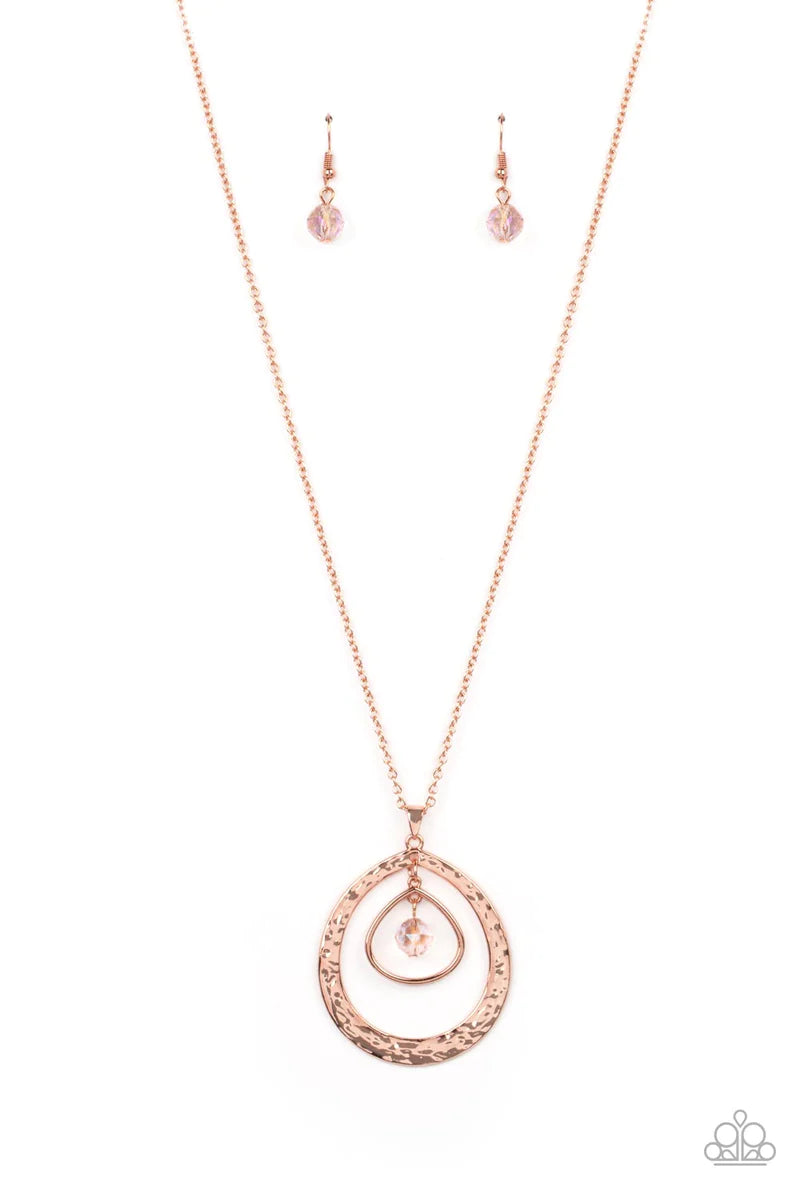 Paparazzi Accessories Tasteful Teardrops - Copper An iridescent peach crystal-like bead twinkles from the top of two mismatched shiny copper teardrop frames at the bottom of an extended shiny copper chain, resulting in a tasteful and timeless pendant. Fea