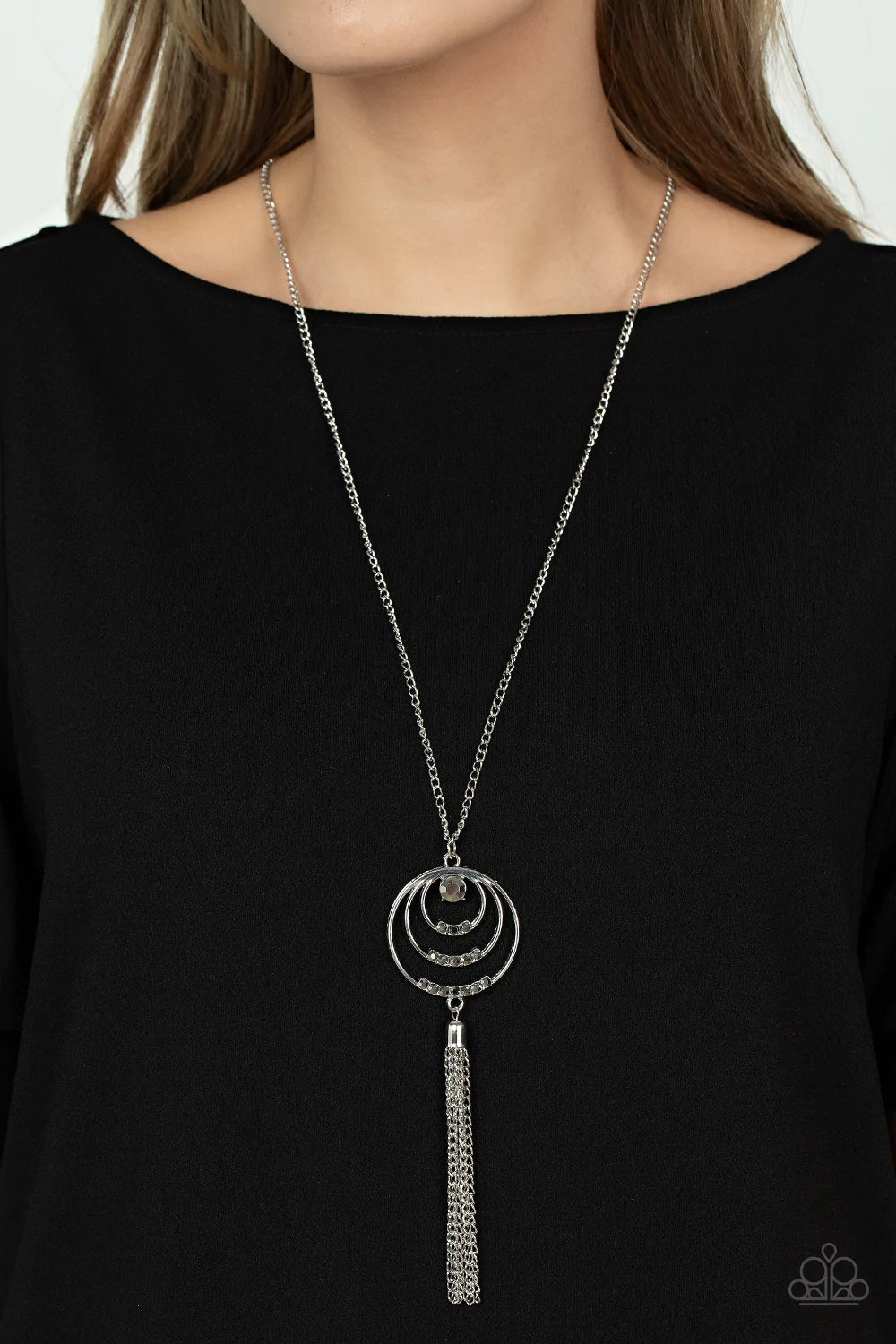 Paparazzi Accessories Spiraling Sparkle - Silver Embellished with rows of hematite rhinestones, concentric silver hoops connect into a single pendant at the bottom of a silver chain. A glistening silver chain tassel swings from the bottom of the display a